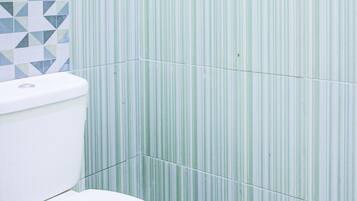 Une salle de bain avec des toilettes, des murs à rayures vertes et des carreaux de sol à motifs.