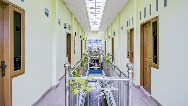 Ein Hotelkorridor mit Oberlicht, Holztüren und einer zentralen Treppe.