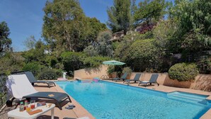 A swimming pool with lounge chairs and a table with drinks and snacks. - Apartment, 1 bedroom, Shared pool, Private beach, Mediterranean garden (La Croix-Valmer)