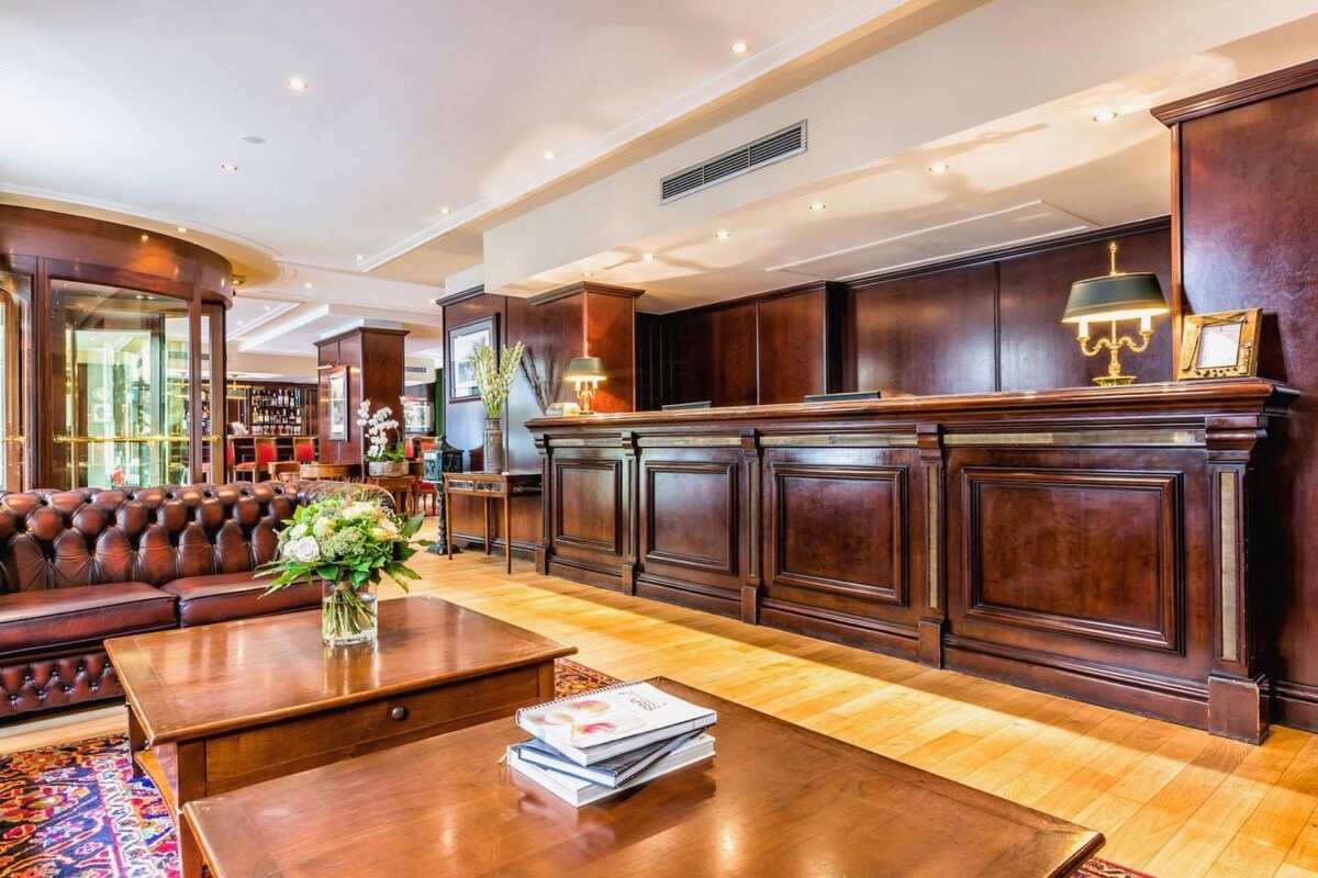 A spacious lobby with a leather sofa, wooden reception desk, and a bookshelf.