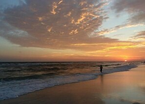 Une scène de plage avec des vagues et un coucher de soleil.