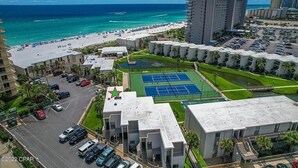 Ein Hotel mit Tennisplatz, Parkplatz und Blick auf Strand und Meer.