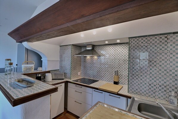 A compact kitchen with a built-in stove, a sink, and a wooden ceiling beam. - Apartment 100m2, Shared pool, Private beach, Mediterranean garden (La Croix-Valmer)