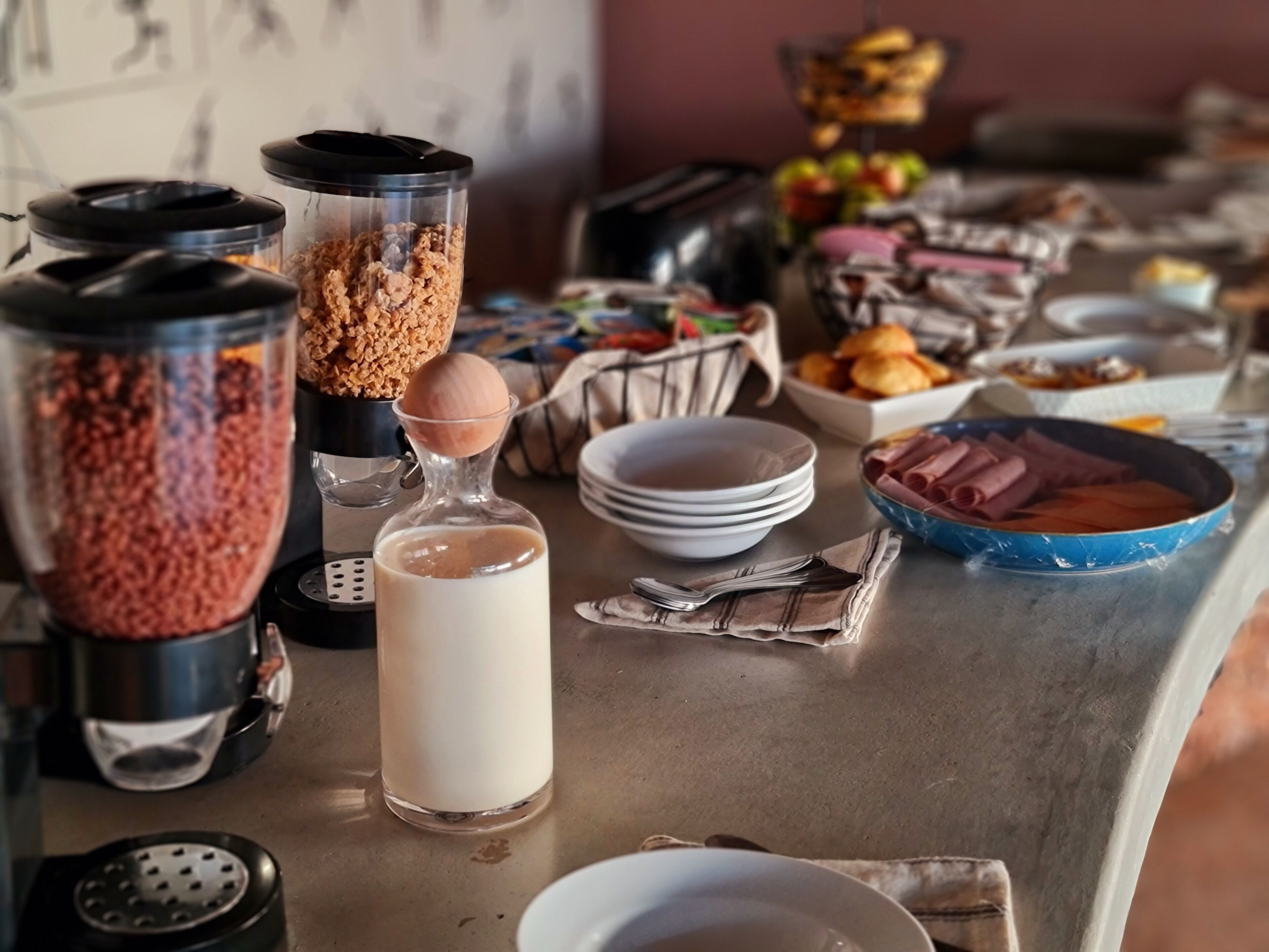 A breakfast buffet with various food items and a milk dispenser.