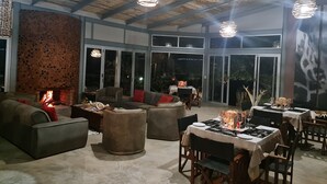 A spacious indoor area with a fireplace, comfortable seating, and a dining setup. - Mountain Peak Game Lodge Namibia (Outjo)