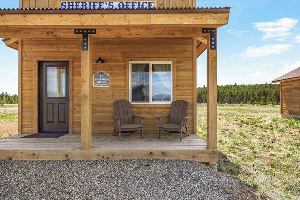 A wooden building labeled 'Sheriff's Office' with a porch, two chairs, a door, and a window.