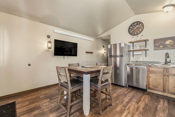 Una cocina moderna con una mesa de comedor de madera, electrodomésticos integrados y un reloj de pared.