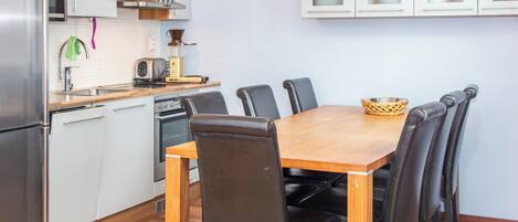 A compact kitchen with a dining table, chairs, and basic appliances.