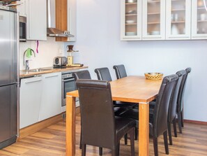 Une cuisine de taille réduite comprenant une table à manger, des chaises et les appareils électroménagers de base.