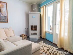Een woonkamer met een beige bank, een open haard en een raam met gordijnen.