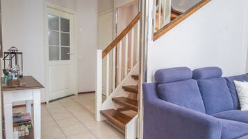 A living room with a blue sofa, a wooden staircase, and a white door.