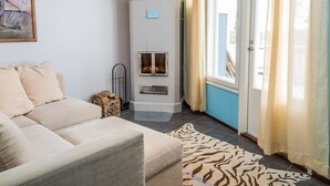 A living room with a beige sofa, a fireplace, and a window with curtains.