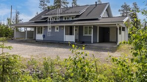 A two-story house with a covered porch, a garage, and a gravel driveway.