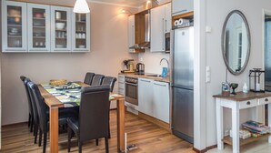 A compact kitchen with a dining area, featuring cabinets, a refrigerator, and a dining table with chairs.