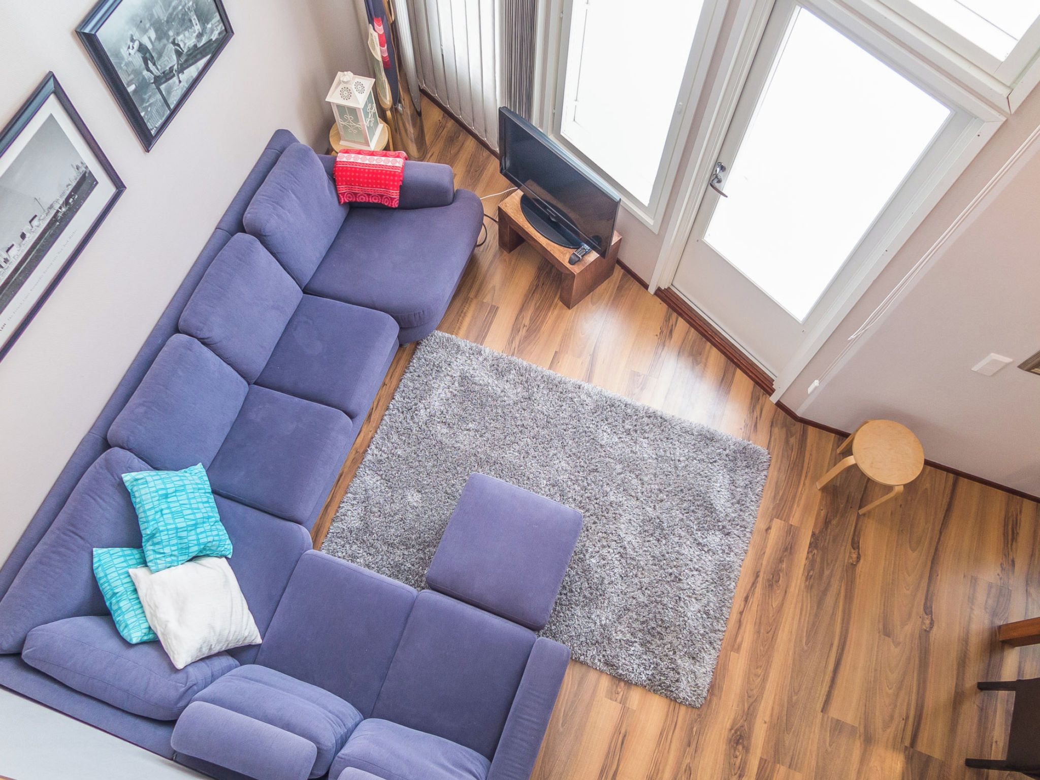 Una sala de estar moderna con un sofá seccional, una alfombra gris y un televisor sobre un mueble de madera.