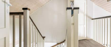 A staircase with white railings and a wooden floor leading to an upper level.