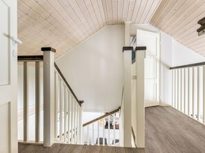 Una escalera con barandillas blancas y piso de madera que lleva a un nivel superior.