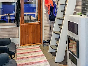 Una sala de estar con una puerta de madera, una chimenea, un tapete a rayas y un juego de escaleras.