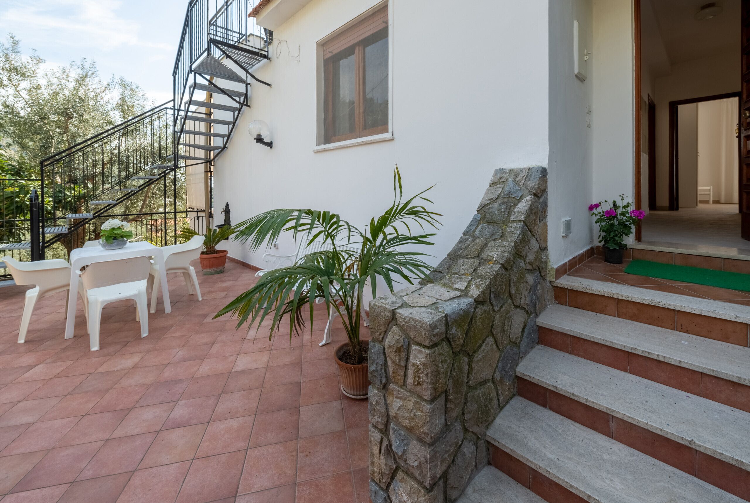 Eine Terrasse mit Sitzgelegenheit, einem Blumentopf und einer Steinmauer.