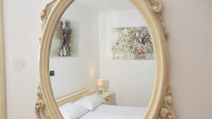 Una camera da letto con un letto, un comodino, una lampada e due opere d'arte appese alle pareti.