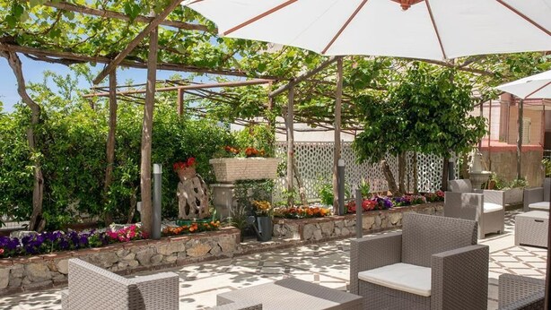 Un'area patio esterna con mobili in vimini e una struttura a pergola.