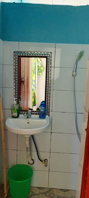 Ein Badezimmer mit Waschbecken, Spiegel, Dusche und einem grünen Mülleimer.