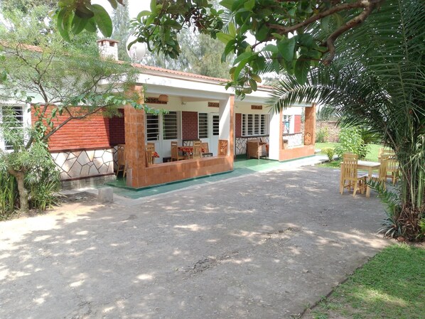 Ein zweistöckiges Haus mit überdachter Terrasse, befestigter Auffahrt und umgebender Bepflanzung.