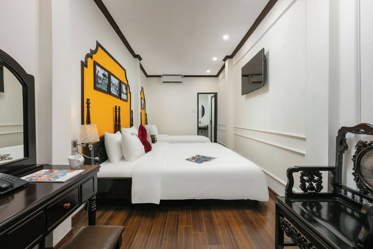 A hotel room with a bed, bedside table, lamp, and a television.
