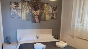 Ein Schlafzimmer mit einem Bett, einem Nachttisch, einer Lampe und abstrakter Wandkunst.