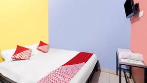 A hotel room with a bed, a TV mounted on the wall, and a small table with a towel. - SPOT ON 91887 Penginapan Rindu (Batam)