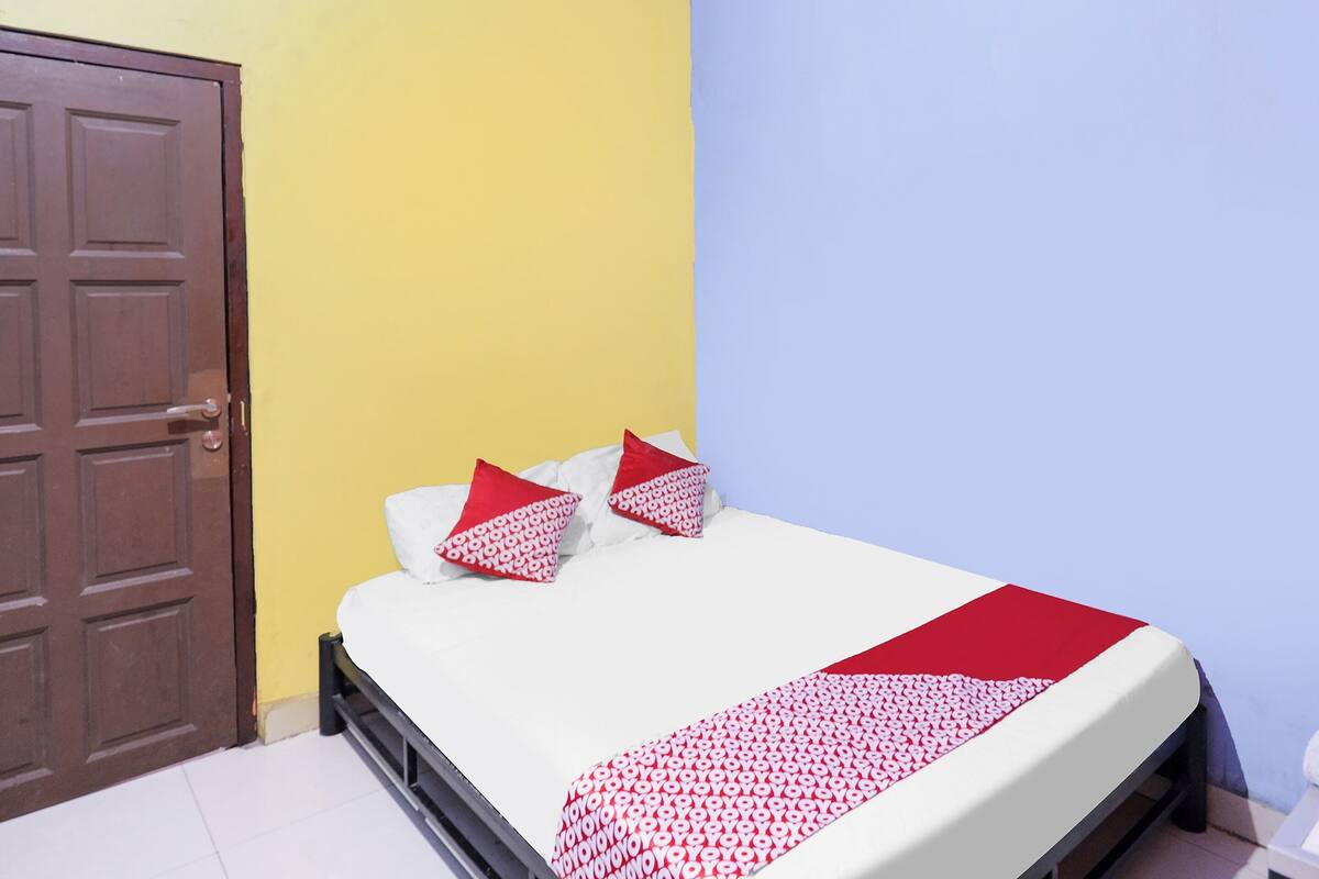 A room with a bed, a door, and a yellow wall.