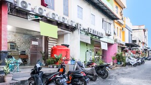 A row of parked motorcycles along a street with buildings featuring various storefronts and air conditioning units. - SPOT ON 91887 Penginapan Rindu (Batam)