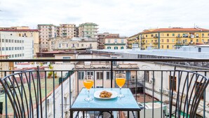 Un balcon avec une table, deux verres de jus d’orange et une assiette de biscuits.