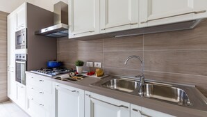 Une cuisine moderne avec des armoires blanches, un évier en acier inoxydable, un four encastré et une casserole bleue sur la cuisinière.