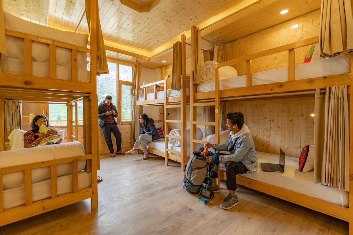 A cabin with bunk beds, a wooden interior, and a person using a laptop.