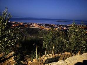 Un pueblo costero al atardecer, con vista al mar y una isla distante.