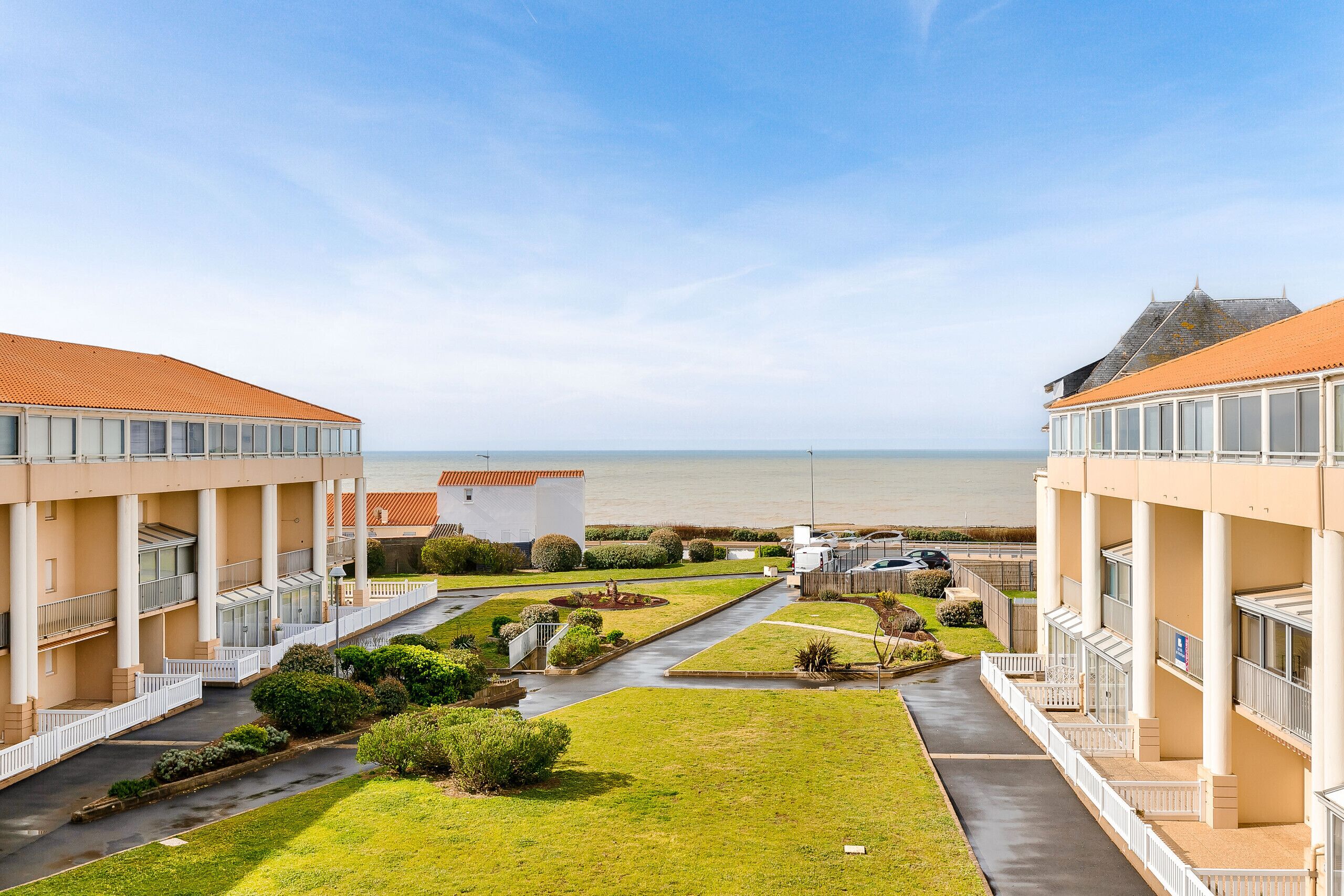 A hotel with a central courtyard, multiple balconies, and a view of the sea.
