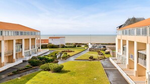 Um hotel com um pátio central, várias varandas e vista para o mar.