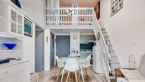 Quarto compacto e bem iluminado, com área de jantar, beliche e escada.