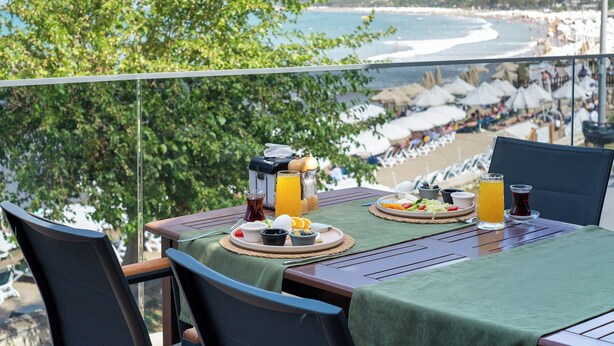 A table set with breakfast items and a view of a beach with umbrellas. - Tropic Beach Club Side  (Manavgat)