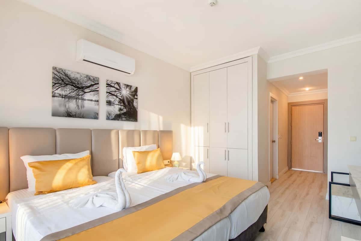 A hotel room with a bed, nightstands, a wardrobe, and a door leading to another room.