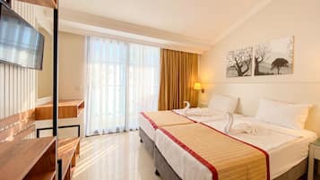 A hotel room with a bed, a desk, a TV, and a window with curtains.