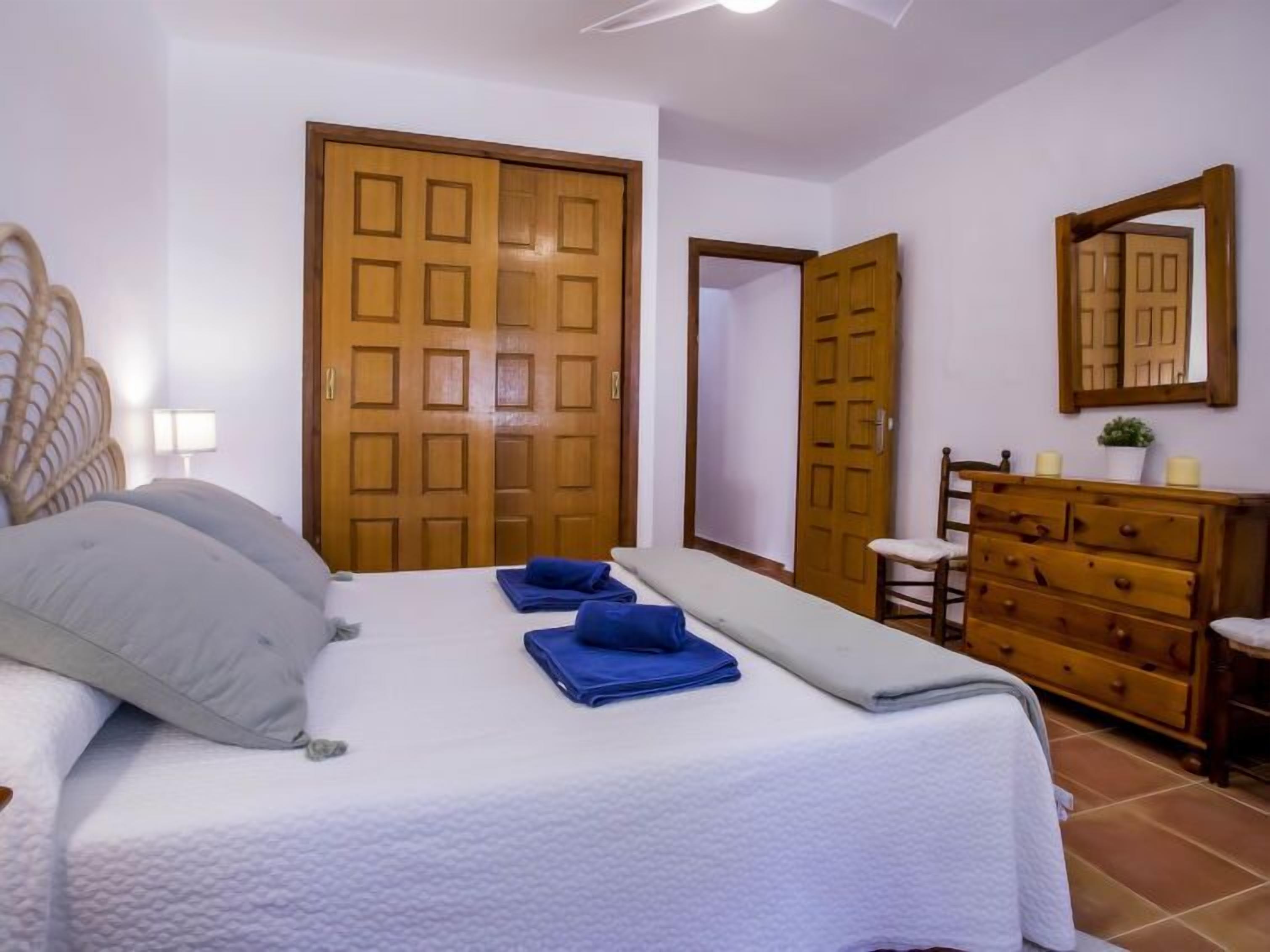 Een slaapkamer met een bed, een dressoir, een spiegel en twee deuren.