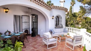 A patio with outdoor seating, a dining area, and a white building with a tiled roof. - Garoe Villa by Interhome (Dénia)