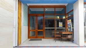 A building entrance with a glass door, a wooden bench, and a tiled floor. - OYO Life 3720 Homestay Gayatri Janti (Malang)