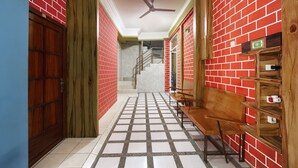 A hallway with red brick walls, a wooden bench, and a ceiling fan. - OYO Life 3720 Homestay Gayatri Janti (Malang)