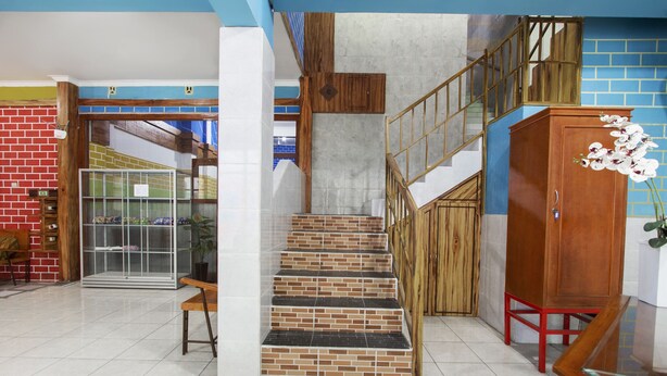 A staircase with a wooden railing, a glass cabinet, and a red chair. - OYO Life 3720 Homestay Gayatri Janti (Malang)