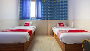 A hotel room with two single beds, a window with blue curtains, and a blue brick wall. - OYO Life 3720 Homestay Gayatri Janti (Malang)