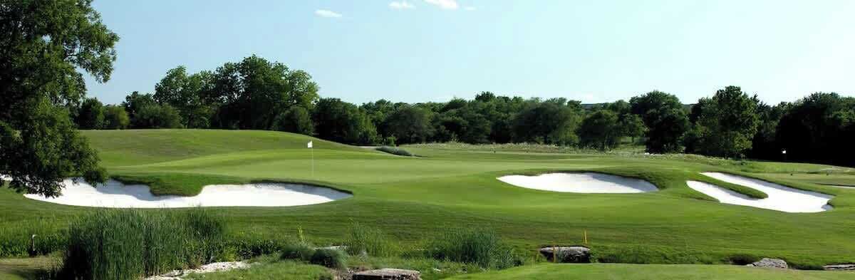 Un parcours de golf avec des bunkers de sable et un mât de drapeau.