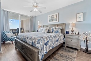A bedroom with a bed, nightstands, a lamp, a chair, and a view of the outdoors.